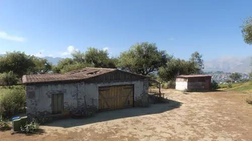 A barn surrounded by trees and a blue sky.