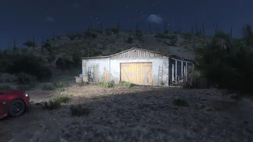 A car shines its lights on a barn.