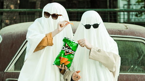 A pair of ghosts in sunglasses eating Doritos